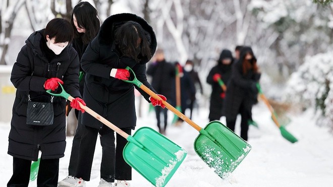 Các giáo viên dọn tuyết trên đường dẫn vào trường học ở thành phố phía Nam Gwangju, Hàn Quốc ngày 21-12-2023